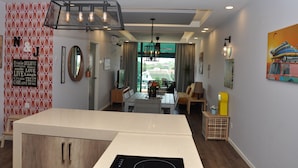 Een moderne keuken met een centraal kookeiland, een eetgedeelte met uitzicht en een zithoek met een bank en salontafel.