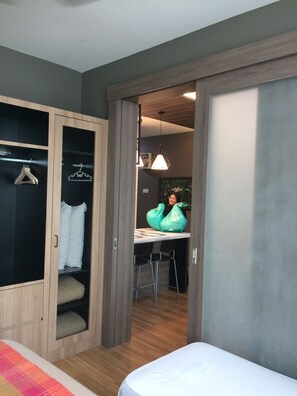 Une chambre à coucher comprenant un lit, une armoire en bois, un bureau avec des chaises et un luminaire suspendu.