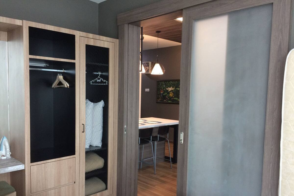 Una habitación de hotel con un armario de madera, una cama, un escritorio y una silla.