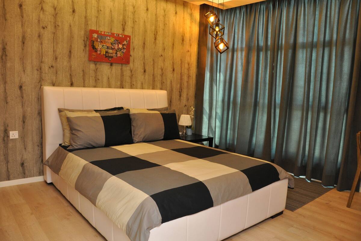 Un dormitorio con una cama grande, paredes de paneles de madera, un adorno colgante en la pared y una ventana con cortinas.