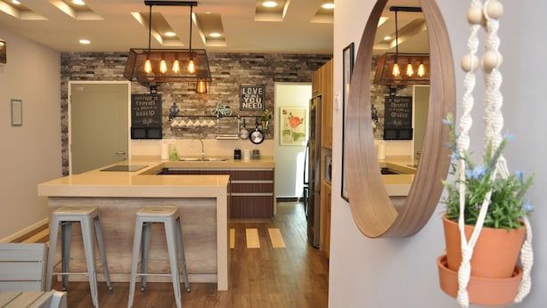 Een moderne keuken met een centraal eiland, barstoelen en een hanglamp.