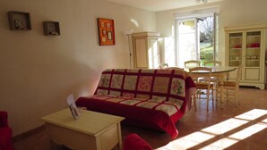Ein gemütliches Wohnzimmer mit einer Couch, einem kleinen Tisch und einem Essbereich mit Stühlen und einem Schrank.