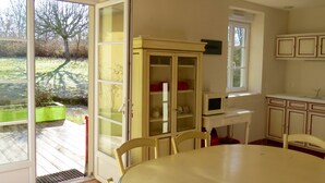 Ein Essbereich mit Tisch, Stühlen, einer Schrank mit Glastüren, einer Mikrowelle und einem Fenster mit Gartenblick.