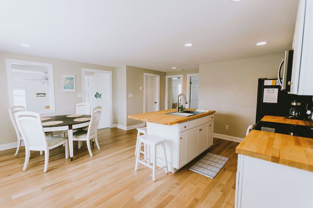 A modern kitchen with white cabinetry, a wooden countertop, and a central island.