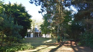 A residential property with a grassy lawn, a pathway, and a house with a covered porch. - rent house in St Briac near golf and beaches, 9 people (Saint-Briac-sur-Mer)