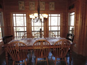 A wooden dining room with a large table, six chairs, and a chandelier.