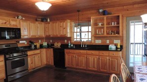 A wooden-paneled kitchen with a stove, oven, and microwave. - River Daze - A Beautiful River Front Brick House O (Ellijay)