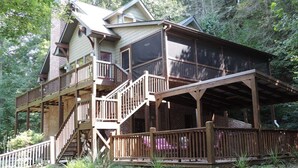 A two-story wooden cabin with a balcony and a covered porch area. - River Daze - A Beautiful River Front Brick House O (Ellijay)