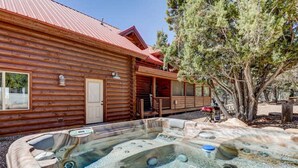 Una cabaña de troncos con un jacuzzi en la parte delantera.