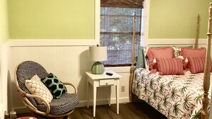 A bedroom with a bed, a chair, a small table, and a window with blinds. - Private Waterfront Family Complex with Dock, Walk to Beach. Angler's Dream. (Tybee Island)