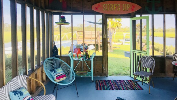 A room with large windows, a sign reading "SURFS UP", and a view of a water body outside. - Private Waterfront Family Complex with Dock, Walk to Beach. Angler's Dream. (Tybee Island)