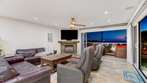 A modern living room with leather sofas, a fireplace, and a large TV. - OCEANFRONT LUXURY—Summer booking fast so Hurry and book!<br> (San Diego)