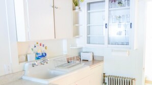 Een moderne keuken met witte kastjes, een dubbele spoelbak en een raam in de muur boven het aanrecht.