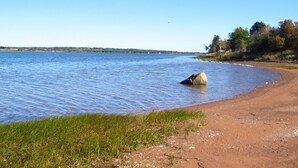 A sandy beach with a large rock in the water, surrounded by grassy areas and trees. - Grandview Beach Cottage, 3 brm , 2 baths, 10Km from S'side, Kayaks. (Miscouche)