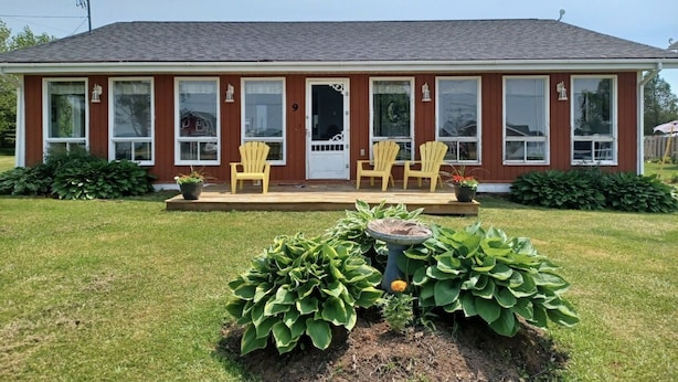 A two-story house with a front porch, three windows on the ground floor, and a door with the number 9. There are two yellow Adirondack chairs on the porch. - Grandview Beach Cottage, 3 brm , 2 baths, 10Km from S'side, Kayaks. (Miscouche)
