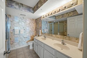 A bathroom with two sinks, a toilet, and a shower.