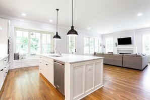 A spacious kitchen with a large island, white cabinetry, and a built-in dishwasher. - Beautiful New Construction Home in Buckhead! Convenience & Luxury! (Atlanta)