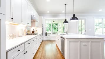 A kitchen with white cabinetry, a large island, and pendant lighting.