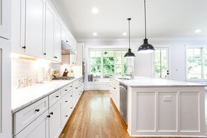A kitchen with white cabinetry, a large island, and pendant lighting. - Beautiful New Construction Home in Buckhead! Convenience & Luxury! (Atlanta)