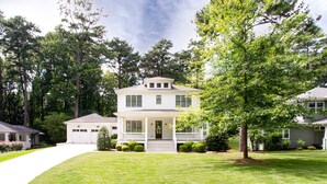 A two-story house with a front porch, a garage, and a well-maintained lawn. - Beautiful New Construction Home in Buckhead! Convenience & Luxury! (Atlanta)