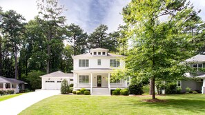 A two-story house with a front porch, a garage, and a well-maintained lawn. - Beautiful New Construction Home in Buckhead! Convenience & Luxury! (Atlanta)
