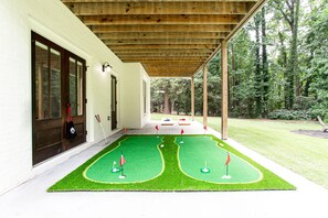 A covered porch with a miniature golf course. - Beautiful New Construction Home in Buckhead! Convenience & Luxury! (Atlanta)