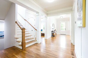 A spacious hallway with hardwood floors, white walls, and a wooden staircase. - Beautiful New Construction Home in Buckhead! Convenience & Luxury! (Atlanta)