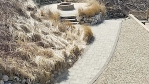 Ein gepflasterter Weg mit einem kreisförmigen Steinrondell und trockenem Gras an beiden Seiten.
