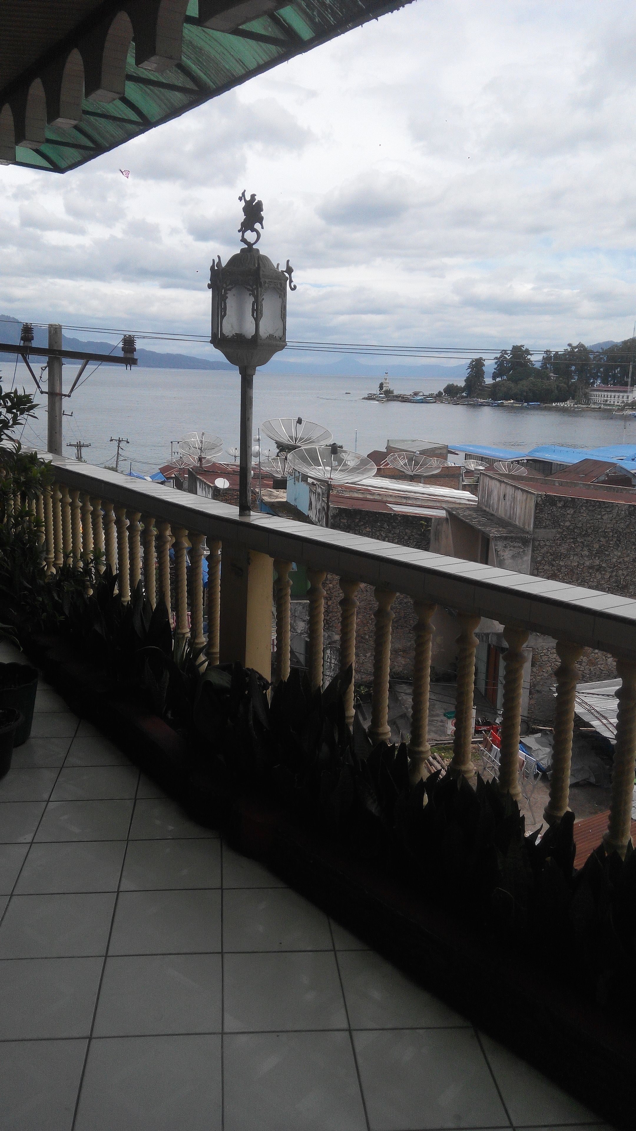 Un balcón con vista al agua, un faro y antenas parabólicas.