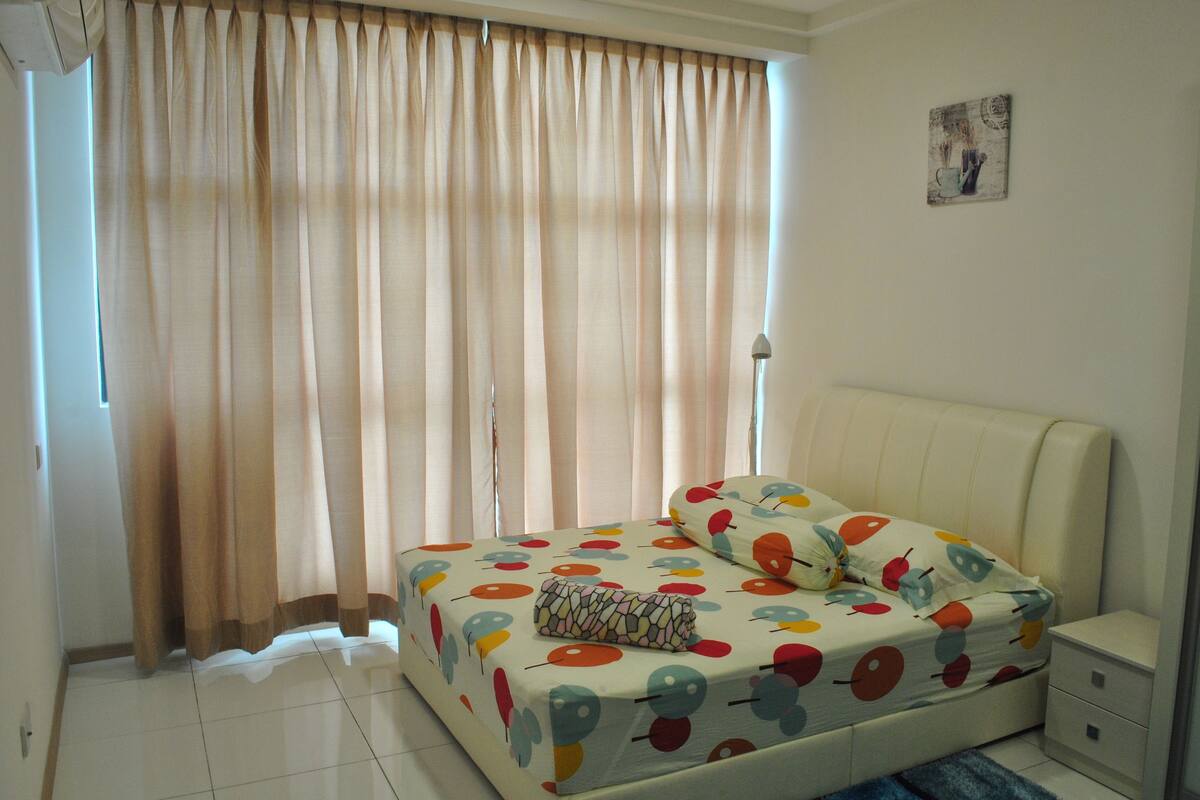 A bedroom with a bed, a nightstand, a lamp, and a window with curtains.
