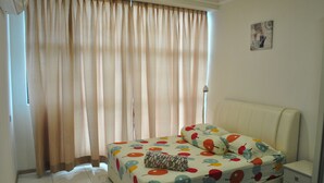 A bedroom with a bed, a nightstand, a lamp, and a window with curtains. - Lawang Suite 2 Bedroom Standard Apartment 2 (Shah Alam)