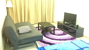 A living room with a sofa, a coffee table, a TV stand, and a large window with curtains. - Lawang Suite 2 Bedroom Standard Apartment 2 (Shah Alam)