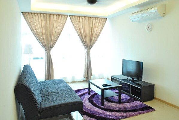 A living room with a sofa, a coffee table, a TV, and a purple rug.