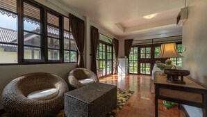 A room with wicker furniture, large windows, and a view of greenery outside. - Doi Inthanon Riverside Resort (Wiang Nong Long)