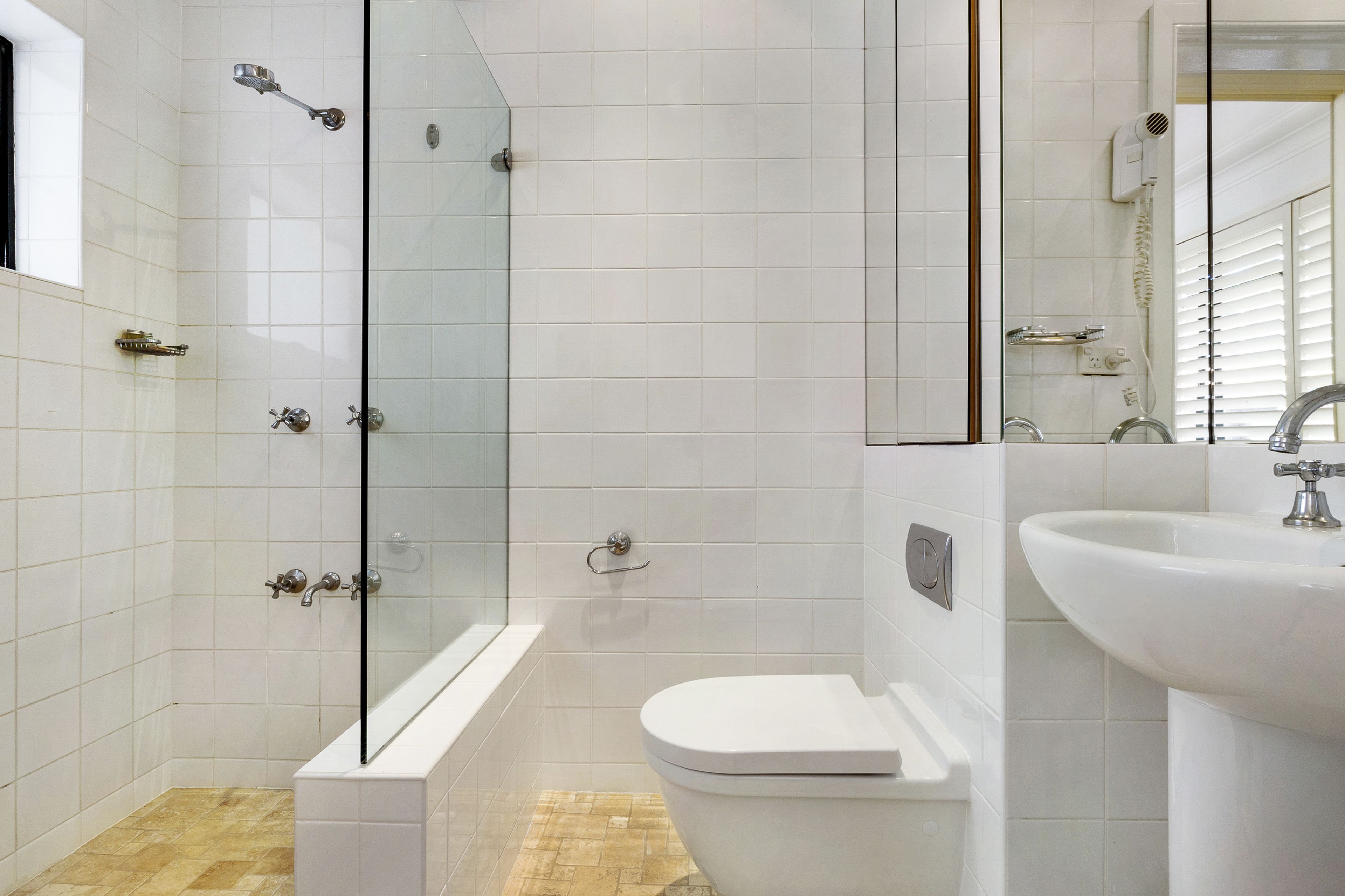 A modern bathroom with a glass-enclosed shower, a bathtub, a toilet, and a sink.