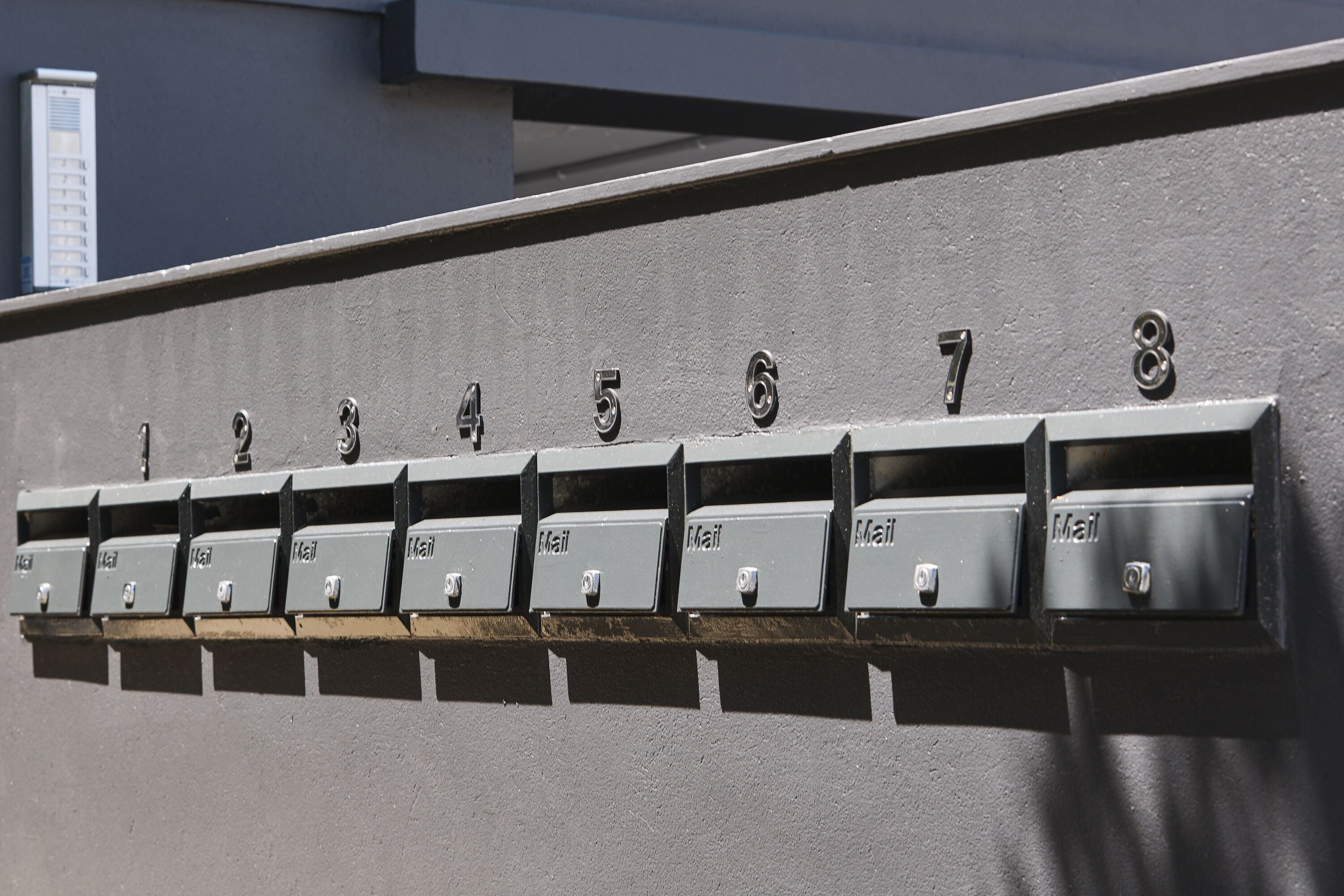 A row of mailboxes numbered 1 to 8 against a wall.