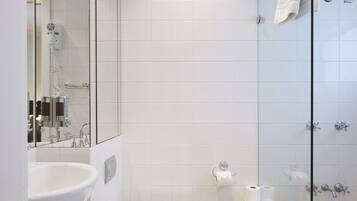 A modern bathroom with a white sink, toilet, and glass-enclosed shower.