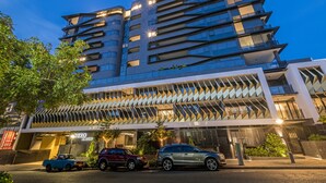 Un bâtiment moderne doté de nombreux balcons et d’une façade aux lignes géométriques.
