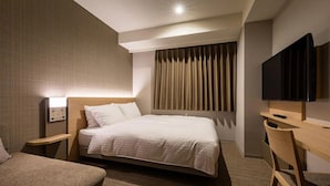 Habitación de hotel con una cama grande, un escritorio, una silla, un televisor y un panel de control en la pared.