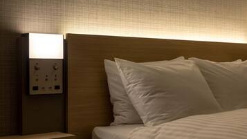 A hotel room with a wooden headboard, a bedside table with a light switch, and a bed with white bedding.