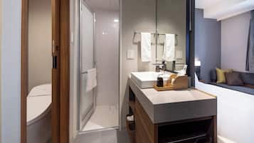 A modern bathroom with a shower, toilet, and a vanity with a mirror.