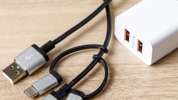 Une multiprise blanche dotée de trois ports USB et d’un câble qui y est connecté.