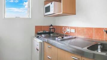 Una cocina compacta equipada con microondas, cafetera y lavamanos.