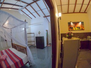 A room with a bed, a wardrobe, a desk, and a painting on the wall. - Girilena Guest House (Hikkaduwa)