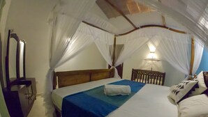 A bedroom with a bed, a nightstand, a mirror, and a canopy bed. - Girilena Guest House (Hikkaduwa)