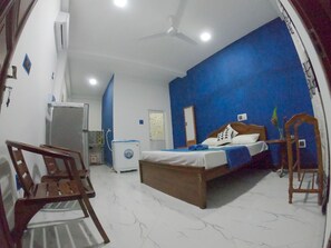 A bedroom with a bed, a desk, a chair, a ceiling fan, and a water dispenser. - Girilena Guest House (Hikkaduwa)