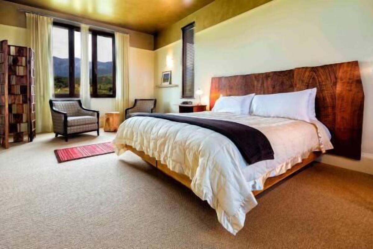 Ein Hotelzimmer mit einem großen Bett, einem Sessel, einem Nachttisch und einem Fenster mit Aussicht.