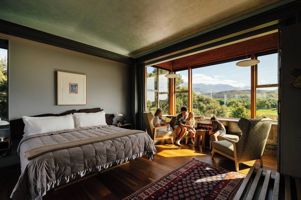 Ein Schlafzimmer mit einem großen Bett, Bergblick und einem Essbereich mit Stühlen.