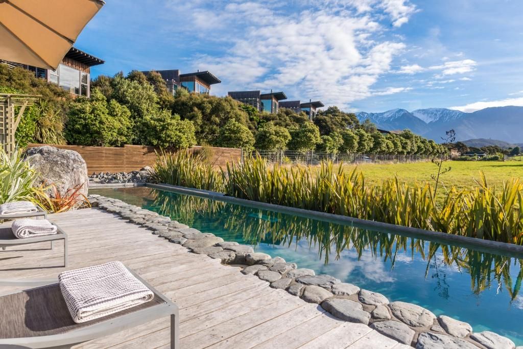 Zona de piscina con terraza de madera, sillas de descanso y toallas.
