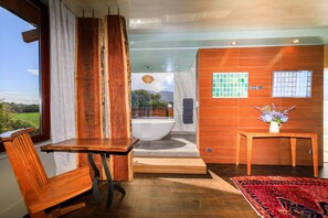A modern bathroom with a large bathtub, wooden accents, and a view of the outdoors.